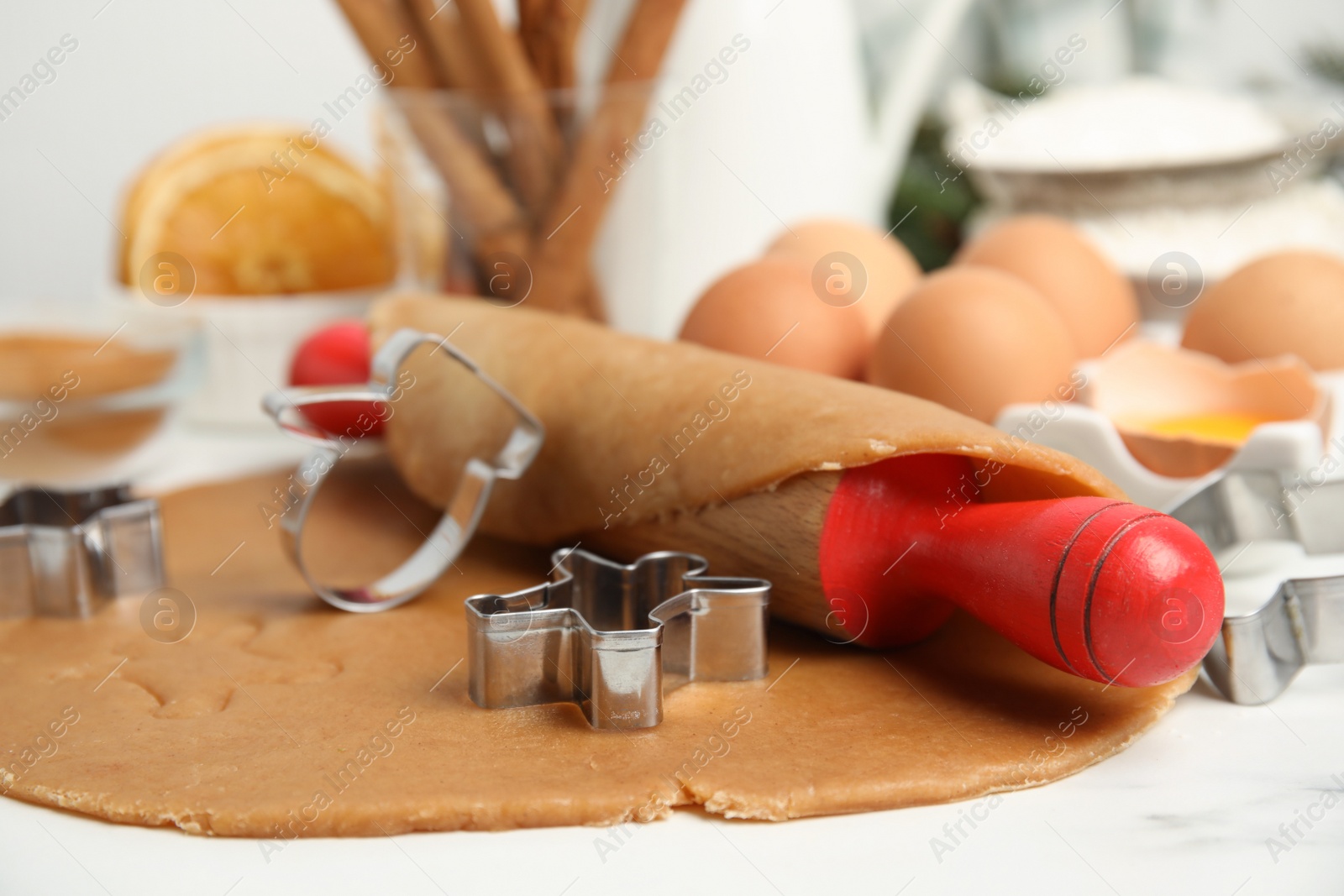 Photo of Cookie cutters, dough and rolling pin on white table, closeup. Christmas biscuits