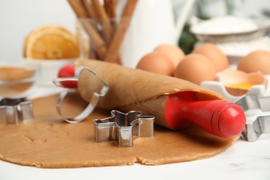 Cookie cutters, dough and rolling pin on white table, closeup. Christmas biscuits