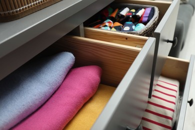 Chest of drawer with different folded clothes indoors, closeup