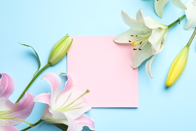 Photo of Flat lay composition with beautiful blooming lily flowers and card on color background