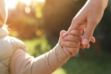 Photo of Daughter holding mother's hand outdoors, closeup view