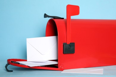 Photo of Open red letter box with envelopes on turquoise background, closeup