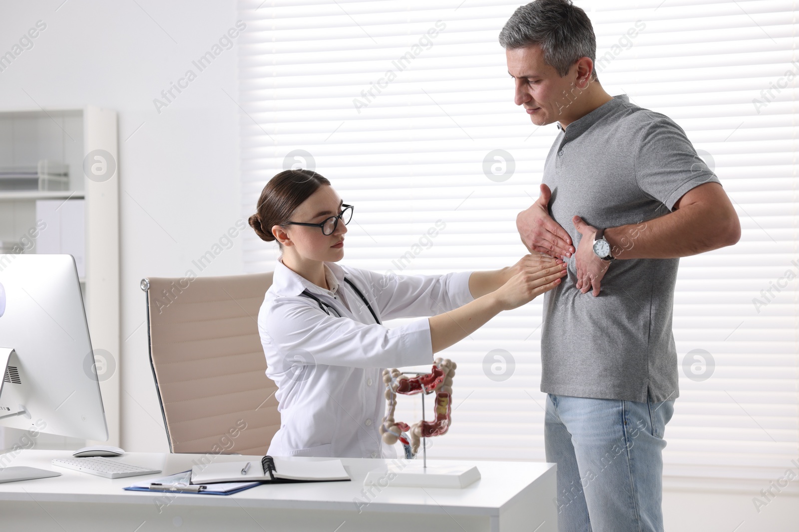 Photo of Gastroenterologist examining patient with stomach pain in clinic