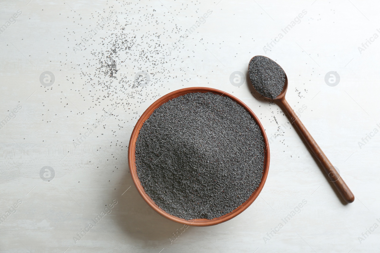 Photo of Bowl and spoon with poppy seeds on white wooden table, flat lay