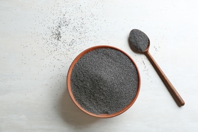 Bowl and spoon with poppy seeds on white wooden table, flat lay