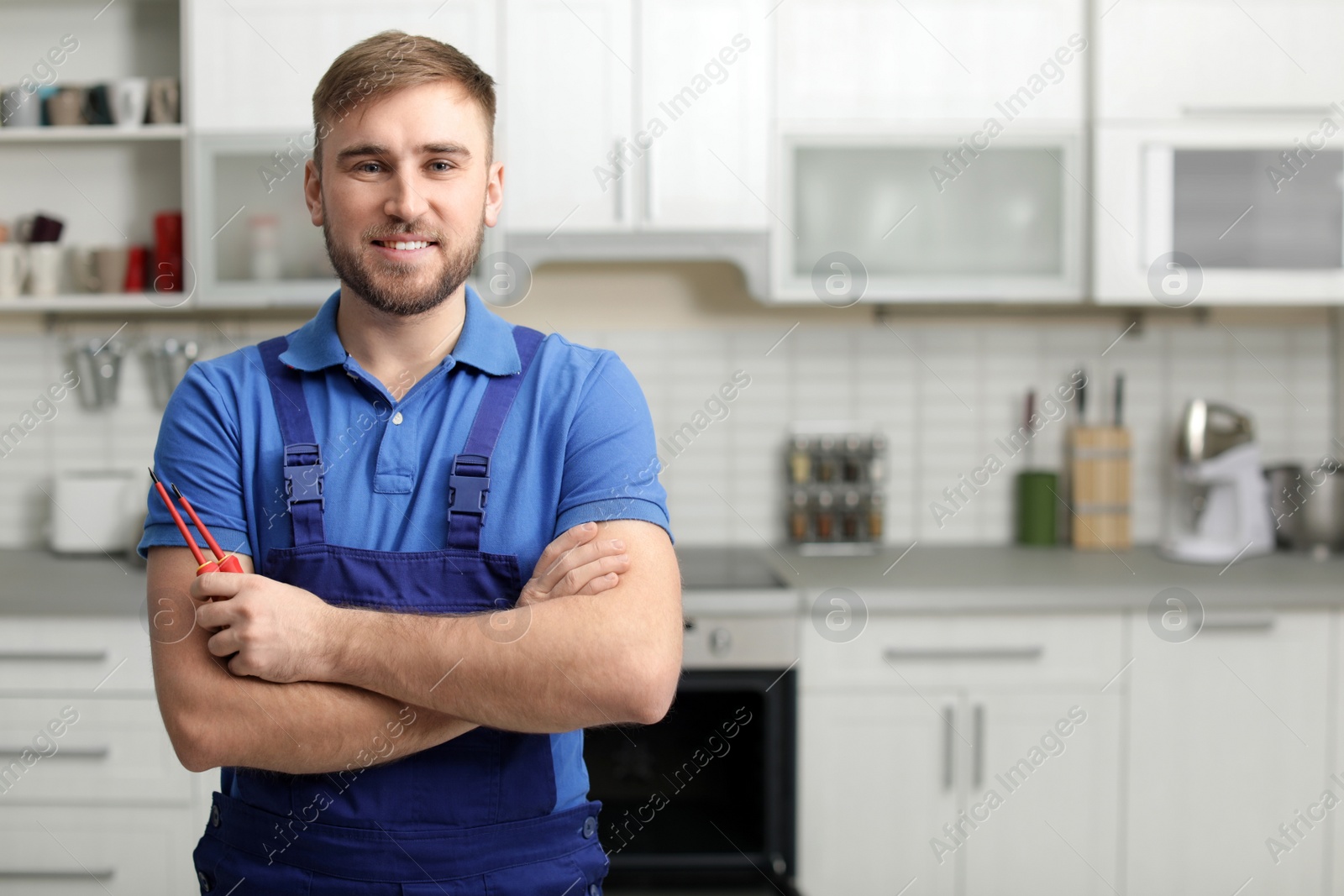 Photo of Portrait of repairman with tools near oven in kitchen. Space for text