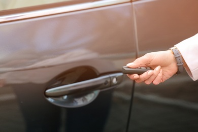 Closeup view of woman opening car door with remote key