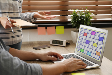 Colleagues working with calendar app on laptop in office, closeup