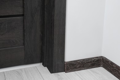Photo of Black wooden plinth with connector on laminated floor near door indoors
