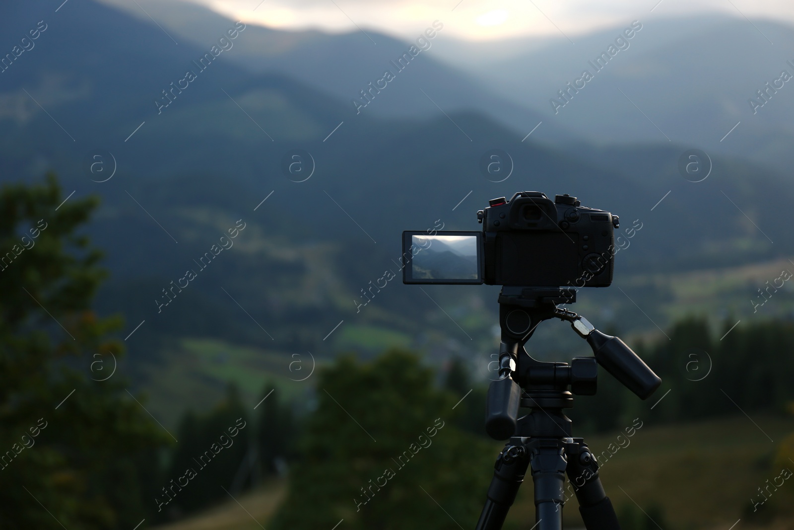 Photo of Taking video with modern camera on tripod in mountains