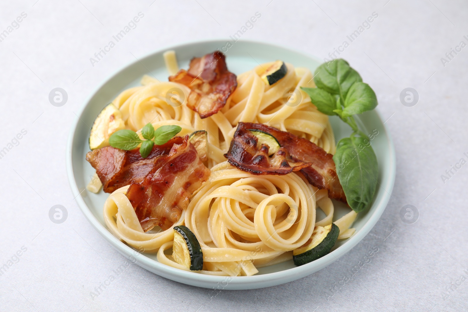 Photo of Tasty pasta with bacon and basil on white table