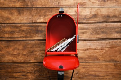 Open red letter box with envelopes against wooden background