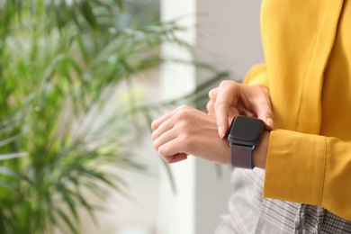 Image of Woman checking stylish smart watch at home, closeup. Space for text