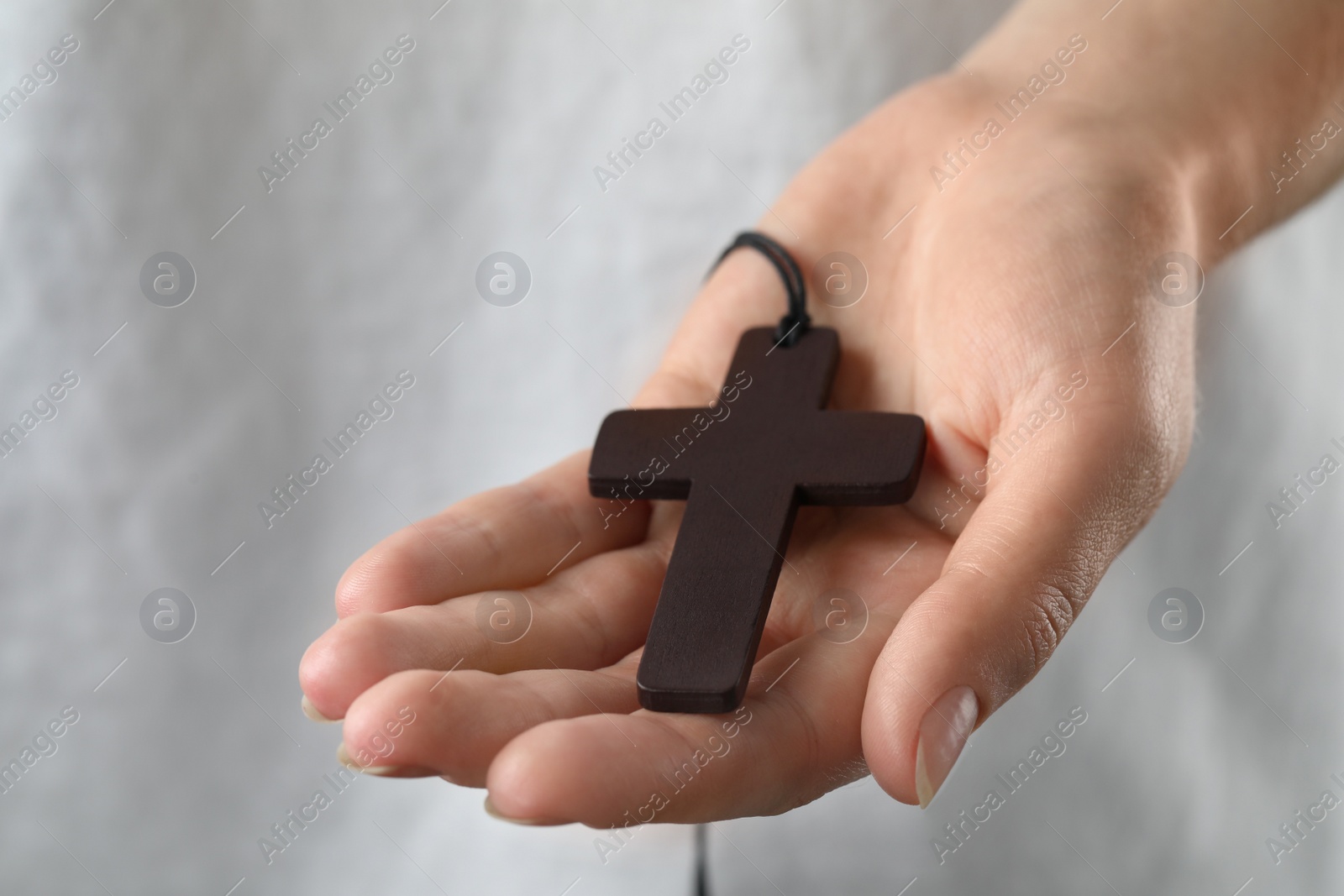 Photo of Woman holding wooden Christian cross, closeup view