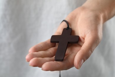 Photo of Woman holding wooden Christian cross, closeup view