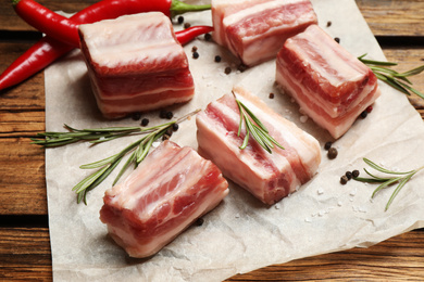 Photo of Raw ribs with rosemary on wooden table