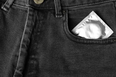 Photo of Packaged condom in dark jeans pocket, closeup. Safe sex
