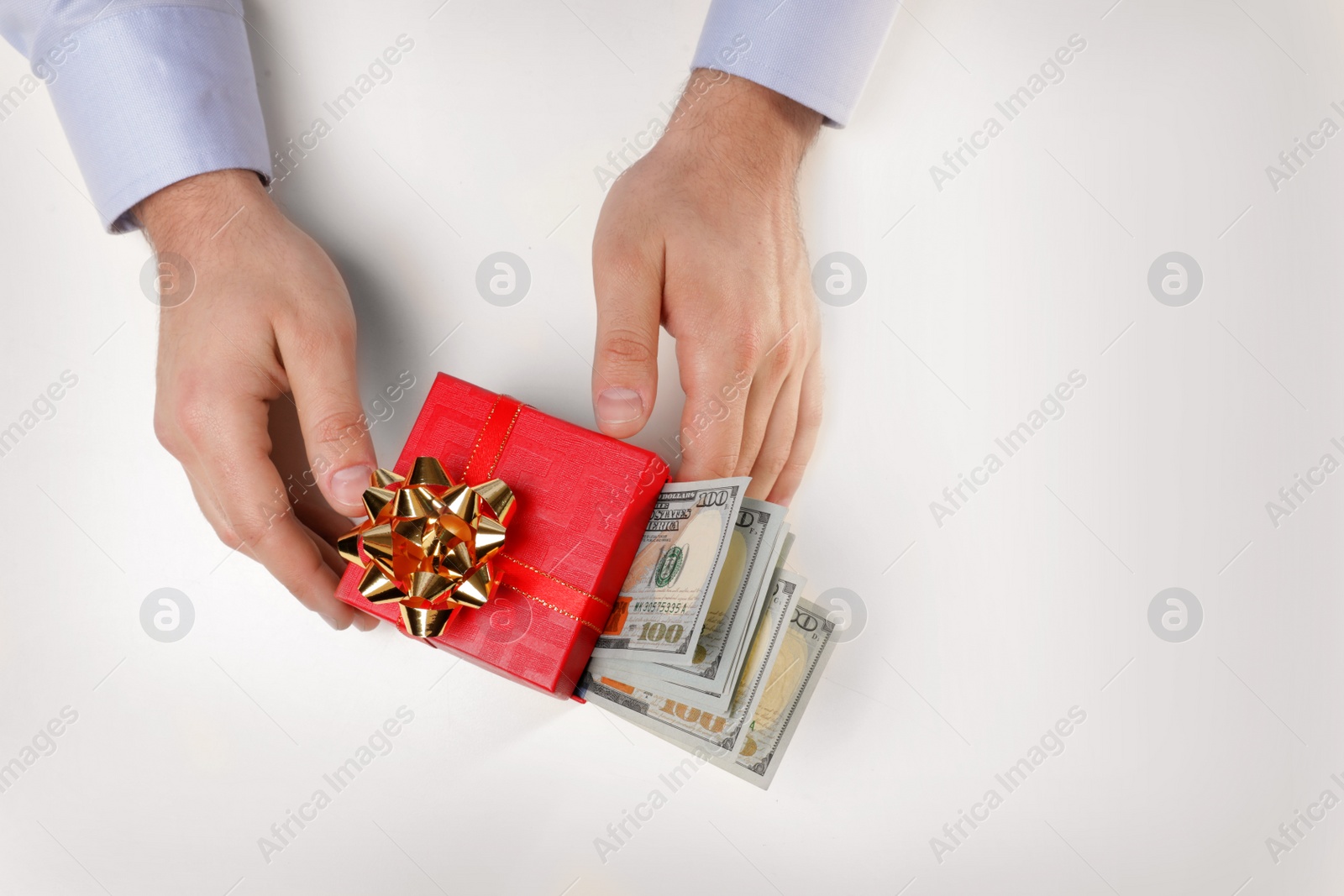 Photo of Man holding gift box with dollar banknotes on white background, top view