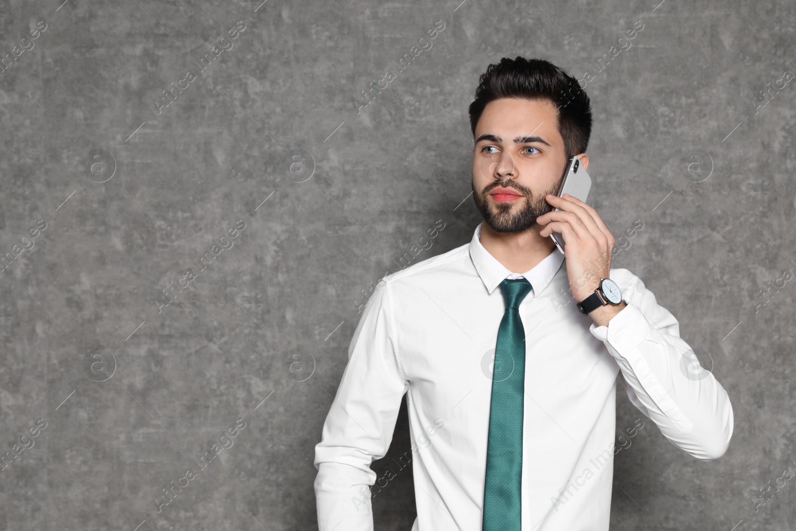 Photo of Portrait of businessman talking on phone against grey background. Space for text