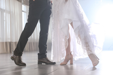 Photo of Newlywed couple dancing together in festive hall, closeup of legs