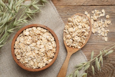 Oatmeal and branches with florets on wooden table, flat lay