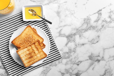 Photo of Plate with toasted bread, honey and glass of juice on light background, top view