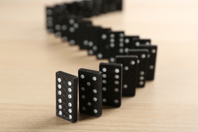 Photo of Black domino tiles with white pips on wooden table