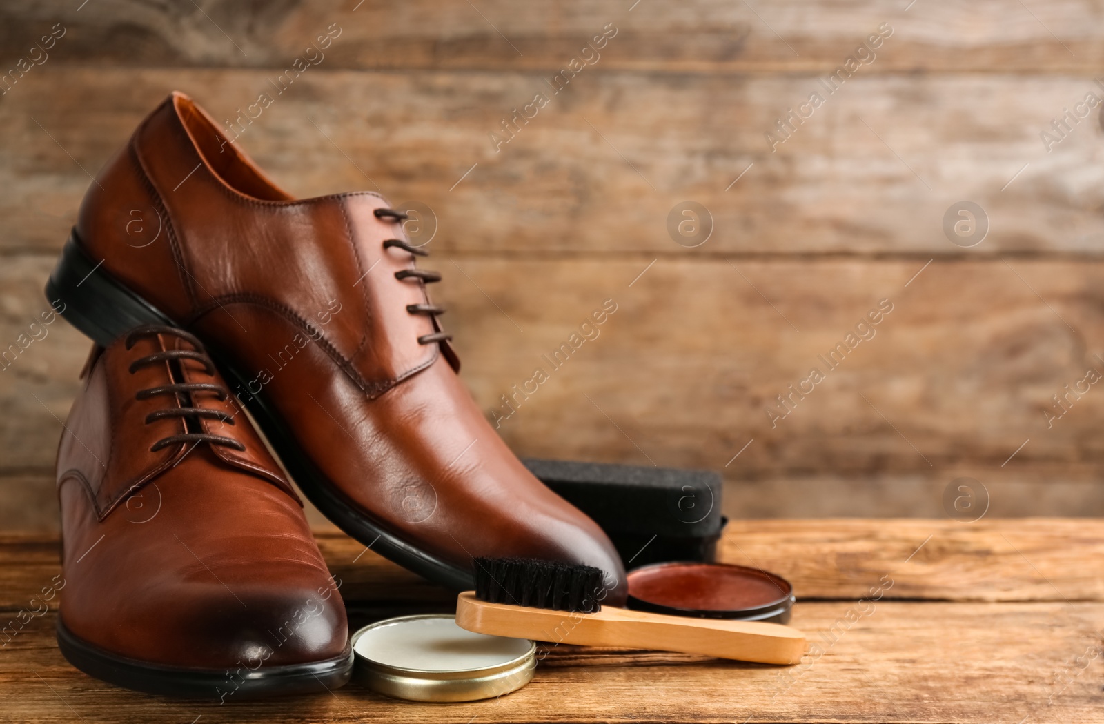 Photo of Shoe care products and footwear on wooden table. Space for text