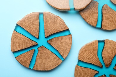 Photo of Stylish wooden cup coasters on light blue background, flat lay