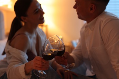 Photo of Affectionate couple with glasses of wine spending time together indoors at night, selective focus. Romantic date