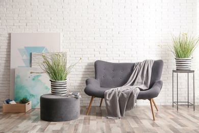 Stylish sofa near brick wall in modern living room interior