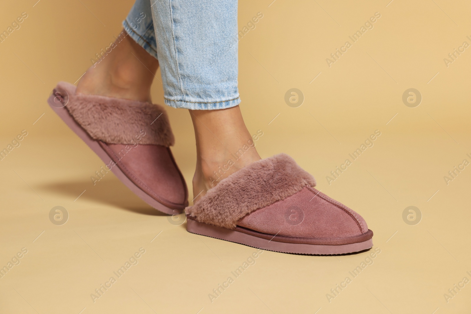 Photo of Woman in warm soft slippers on beige background, closeup