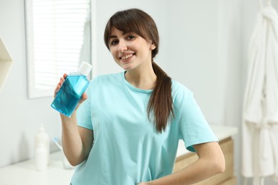 Photo of Young woman with mouthwash in bathroom. Oral hygiene