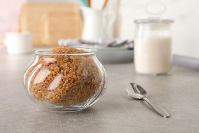 Glass bowl with brown sugar on grey table