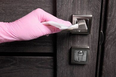 Woman wiping door handle with paper towel, closeup