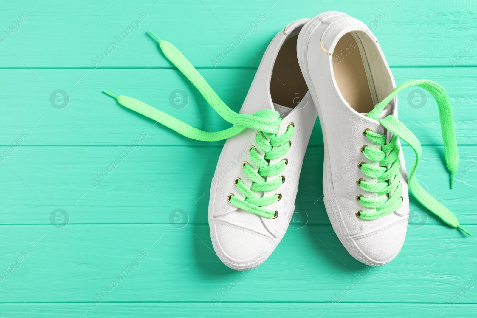 Photo of Pair of stylish shoes with laces on turquoise wooden background, flat lay. Space for text
