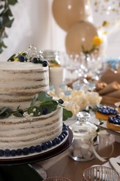 Beautiful cake and other treats on table in room. Sweet buffet