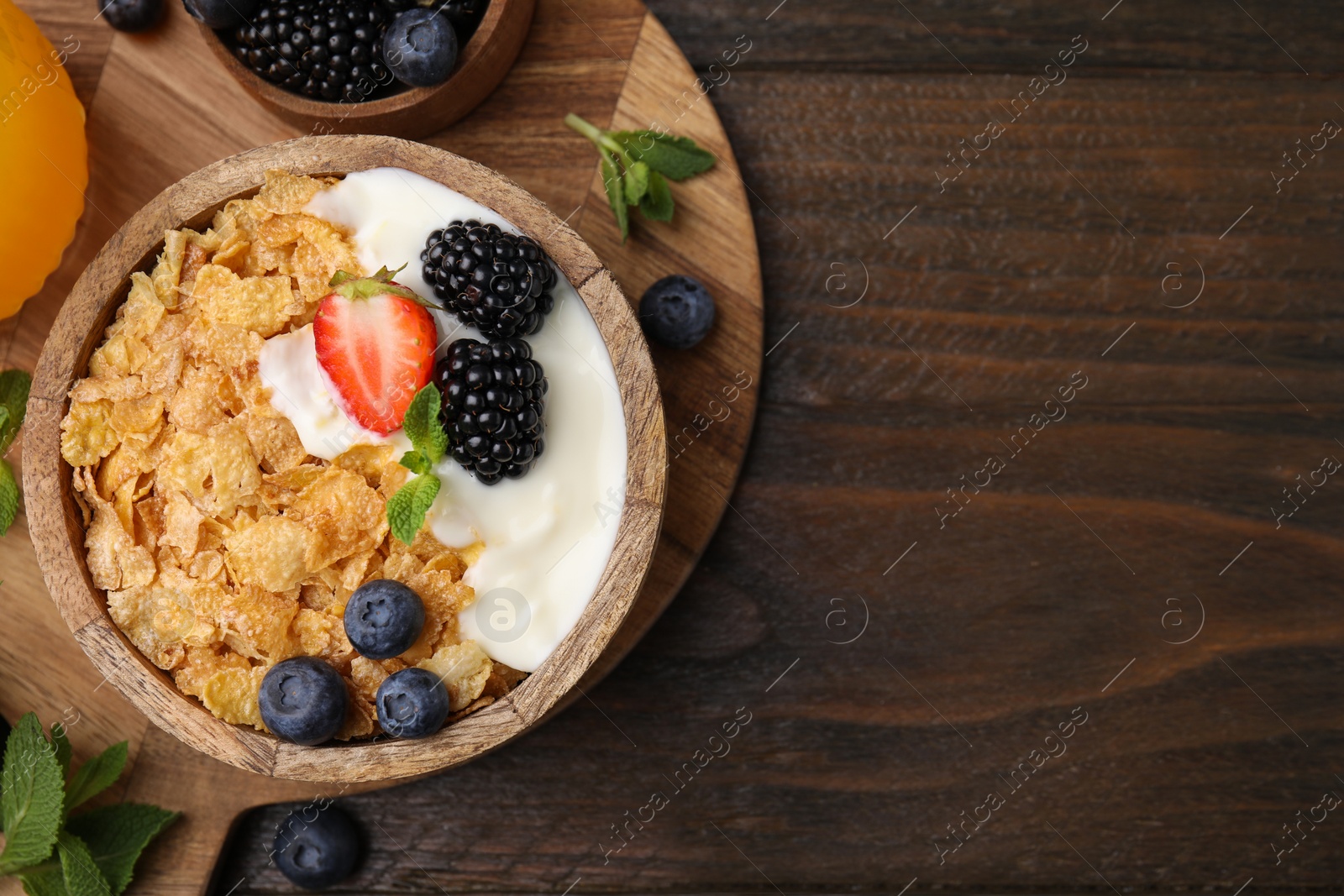 Photo of Delicious crispy cornflakes, yogurt and fresh berries served on wooden table, flat lay with space for text. Healthy breakfast