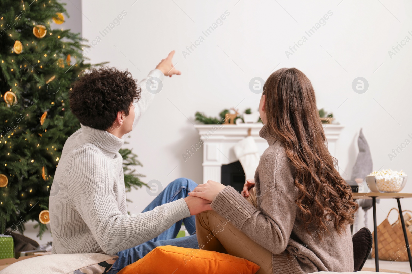 Photo of Couple holding hands together and watching movie via video projector at home