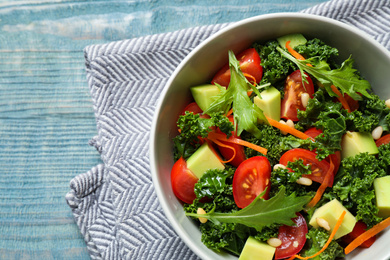 Tasty fresh kale salad on light blue wooden table, flat lay