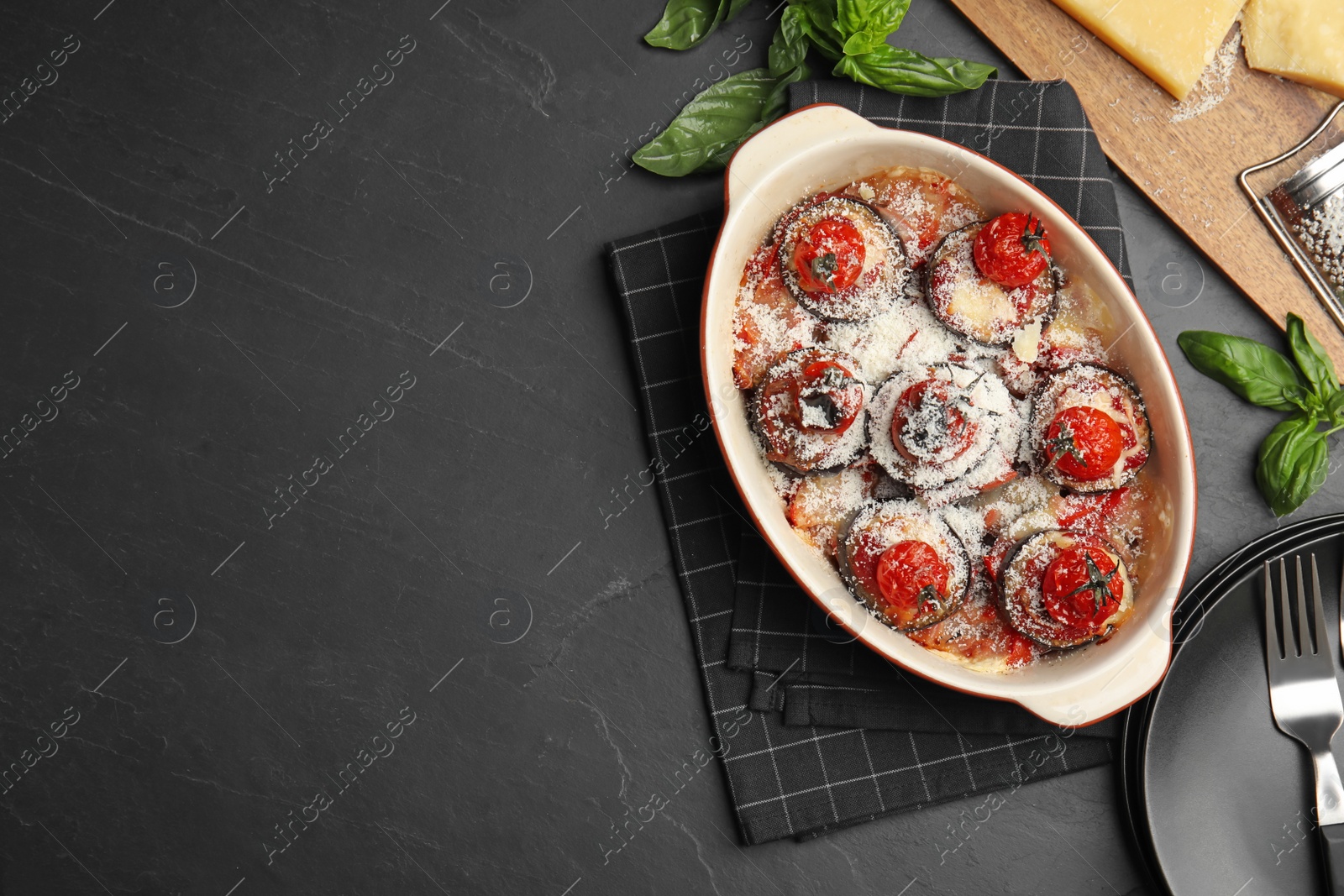 Photo of Baked eggplant with tomatoes and cheese served on black table, flat lay. Space for text