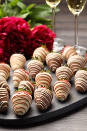 Delicious chocolate covered strawberries, sparkling wine and flowers on wooden table