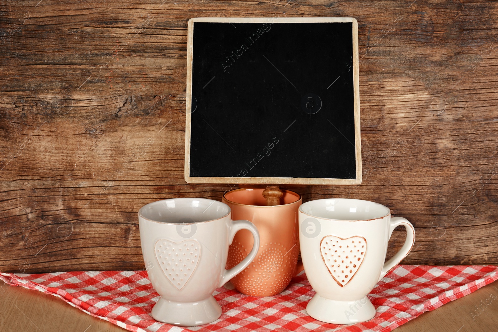 Photo of Ceramic cups on table near small chalkboard