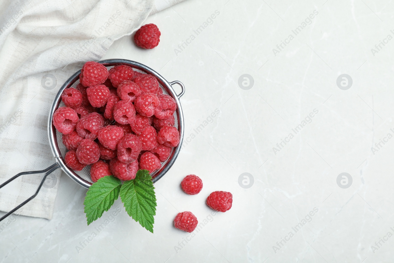 Photo of Sieve with ripe aromatic raspberries on table, top view