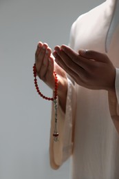 Muslim man with misbaha praying on blurred background, closeup