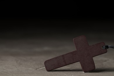 Photo of Wooden Christian cross on grey table, closeup. Space for text