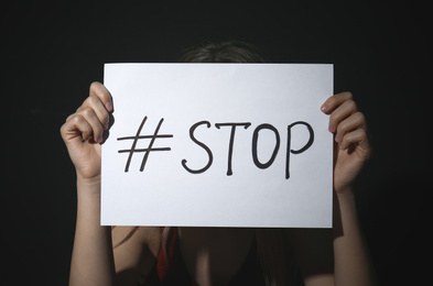 Photo of Young woman with hashtag STOP on black background. Domestic violence concept