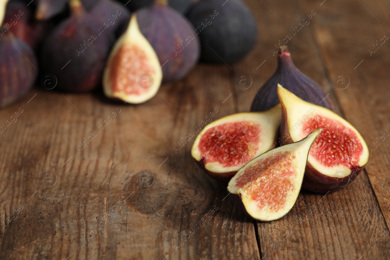 Photo of Whole and cut tasty fresh figs on wooden table, space for text