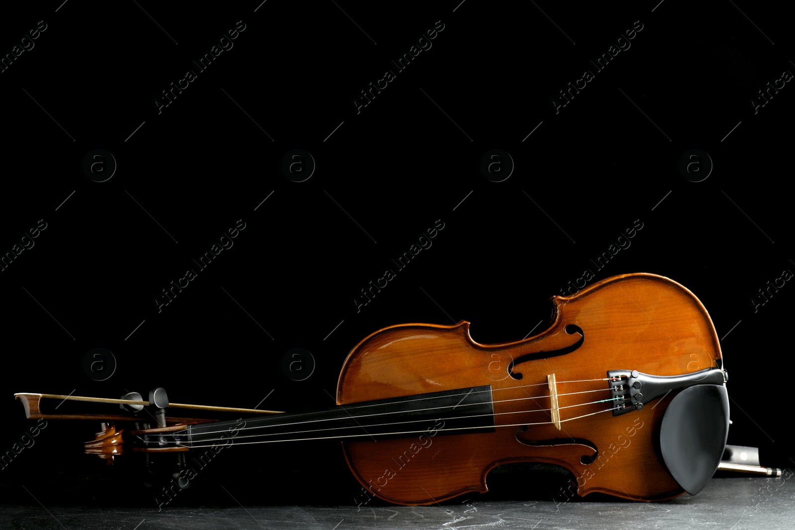 Photo of Classic violin and bow on grey stone table. Space for text