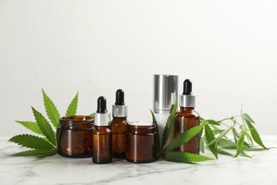 Photo of Composition with CBD oil, THC tincture and hemp leaves on white marble table
